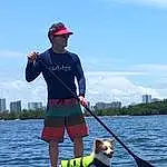 Water, Dog, Sky, Cloud, Dog breed, Lake, Carnivore, Companion dog, Leisure, Boats And Boating--equipment And Supplies, Recreation, Baseball Cap, Fisherman, T-shirt, Water Transportation, Leash, Hat, Fashion Accessory, Surface Water Sports